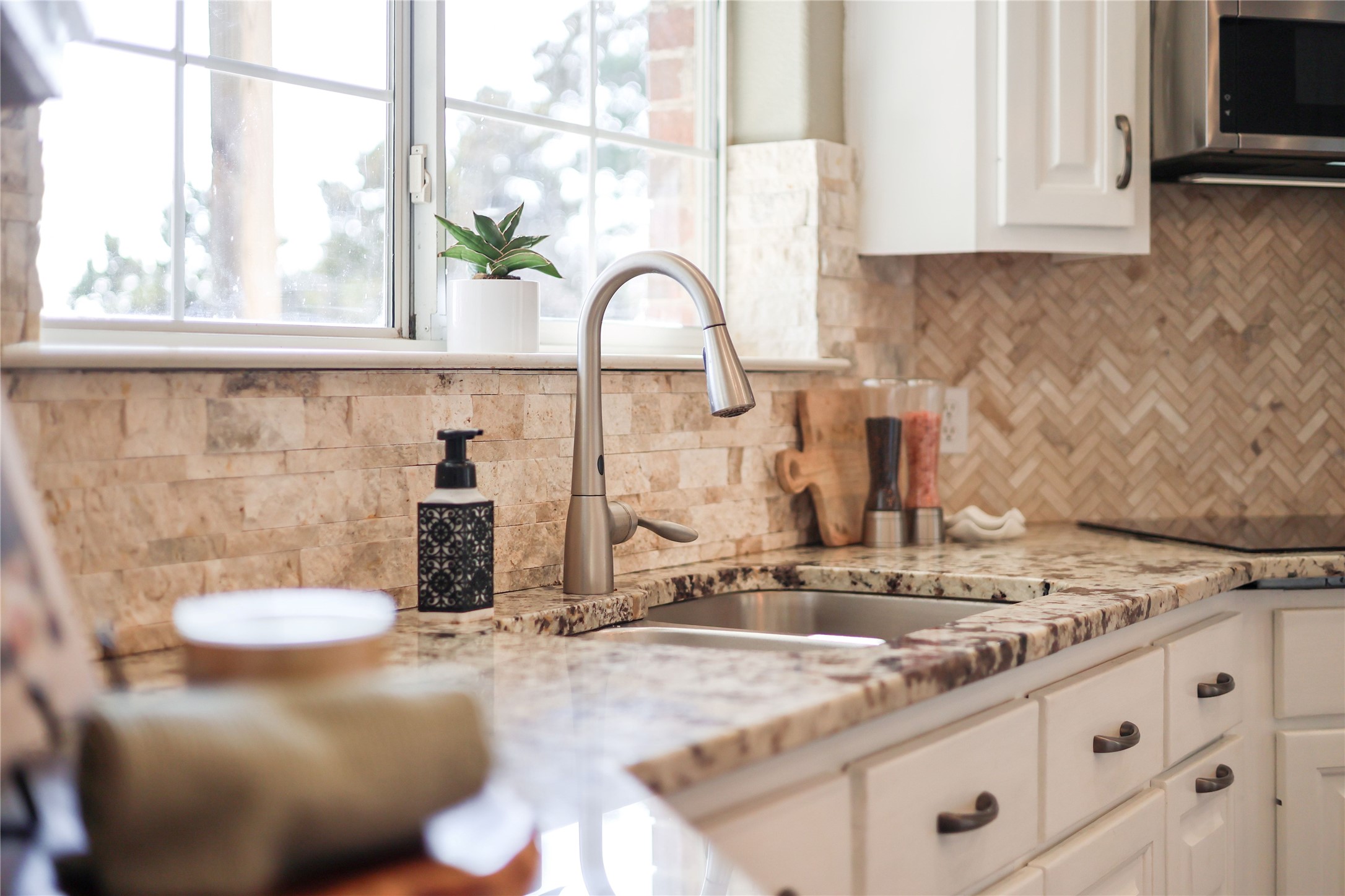 18607 White Rim Trail Jonestown, TX 78645 - Photo 11 of 40 Kitchen with light stone counters, white cabinetry, stainless steel microwave, backsplash, and black electric stovetop