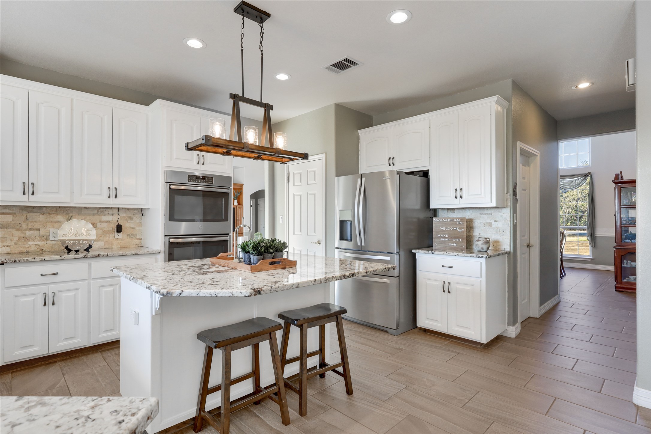 18607 White Rim Trail Jonestown, TX 78645 - Photo 13 of 40 Kitchen with decorative backsplash, a kitchen bar, stainless steel appliances, and light stone counters