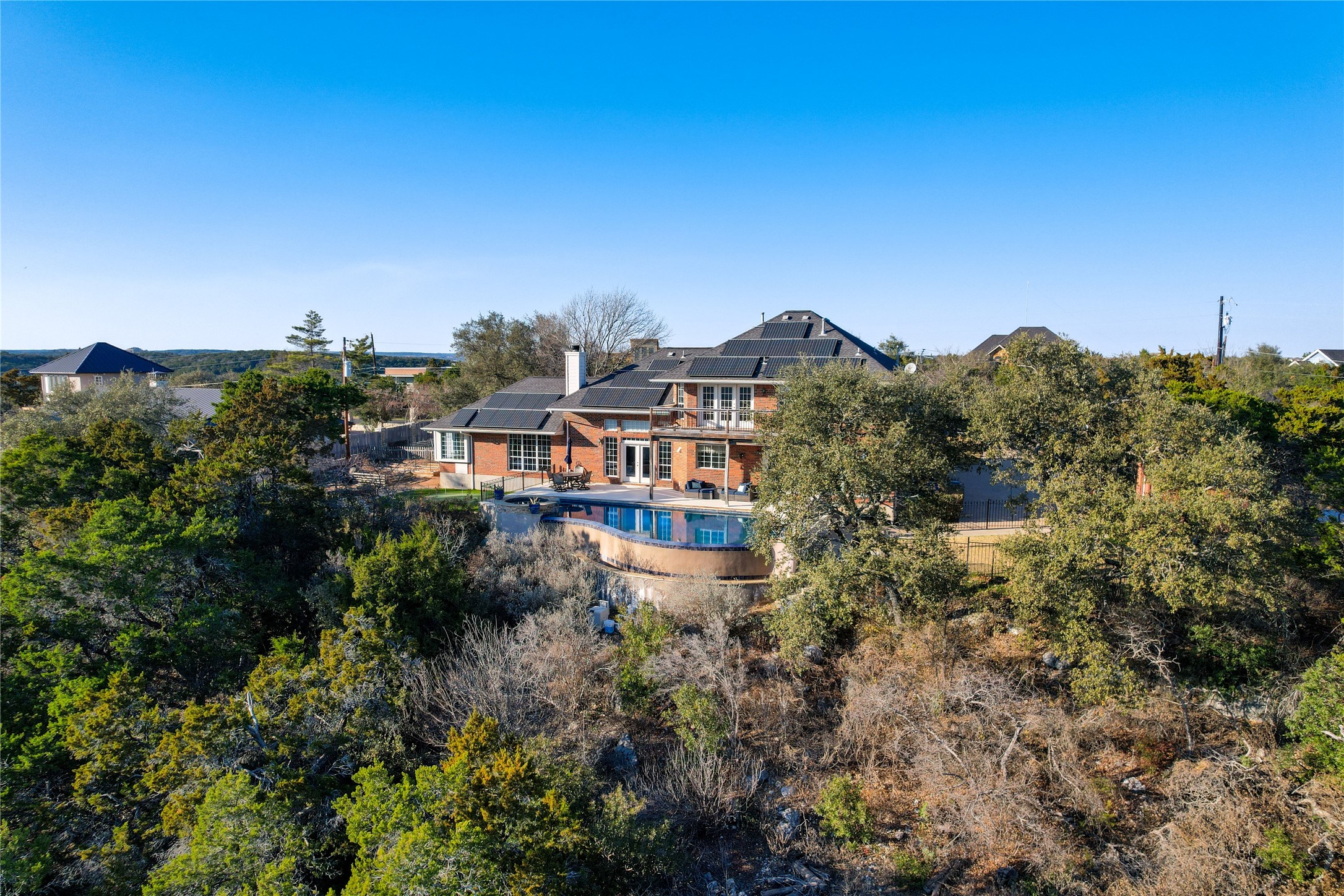 18607 White Rim Trail Jonestown, TX 78645 - Photo 39 of 40 Back of property featuring roof mounted solar panels, an outdoor pool, a chimney, and a patio area