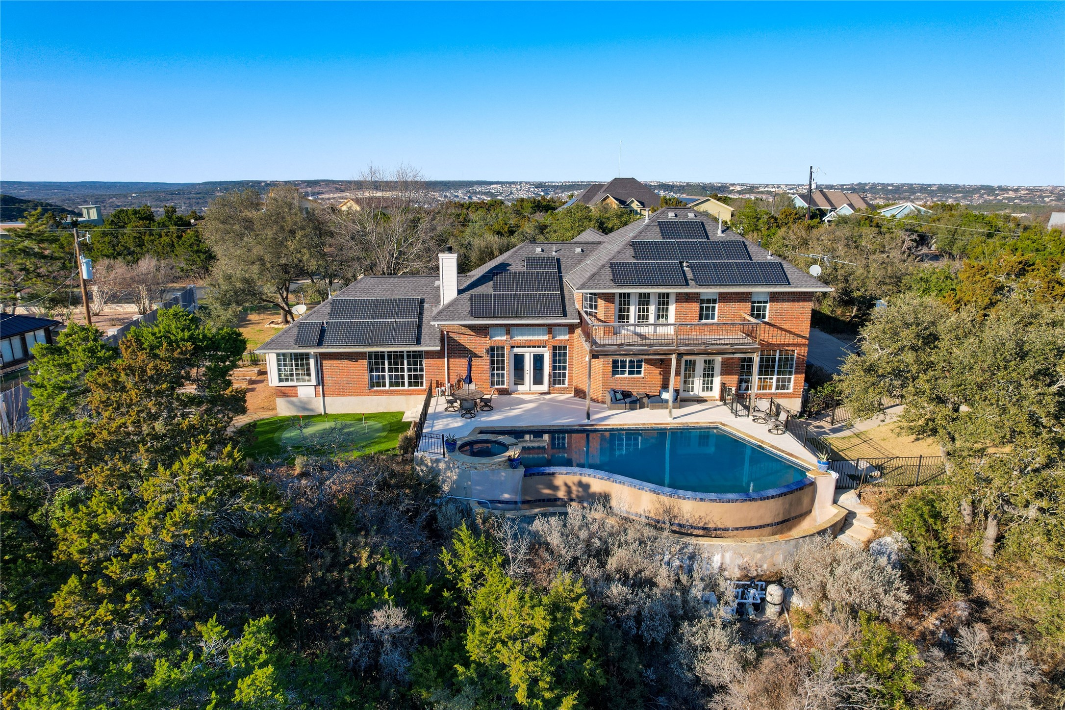 18607 White Rim Trail Jonestown, TX 78645 - Photo 40 of 40 Back of property featuring roof mounted solar panels, a fenced backyard, a patio, a chimney, and french doors