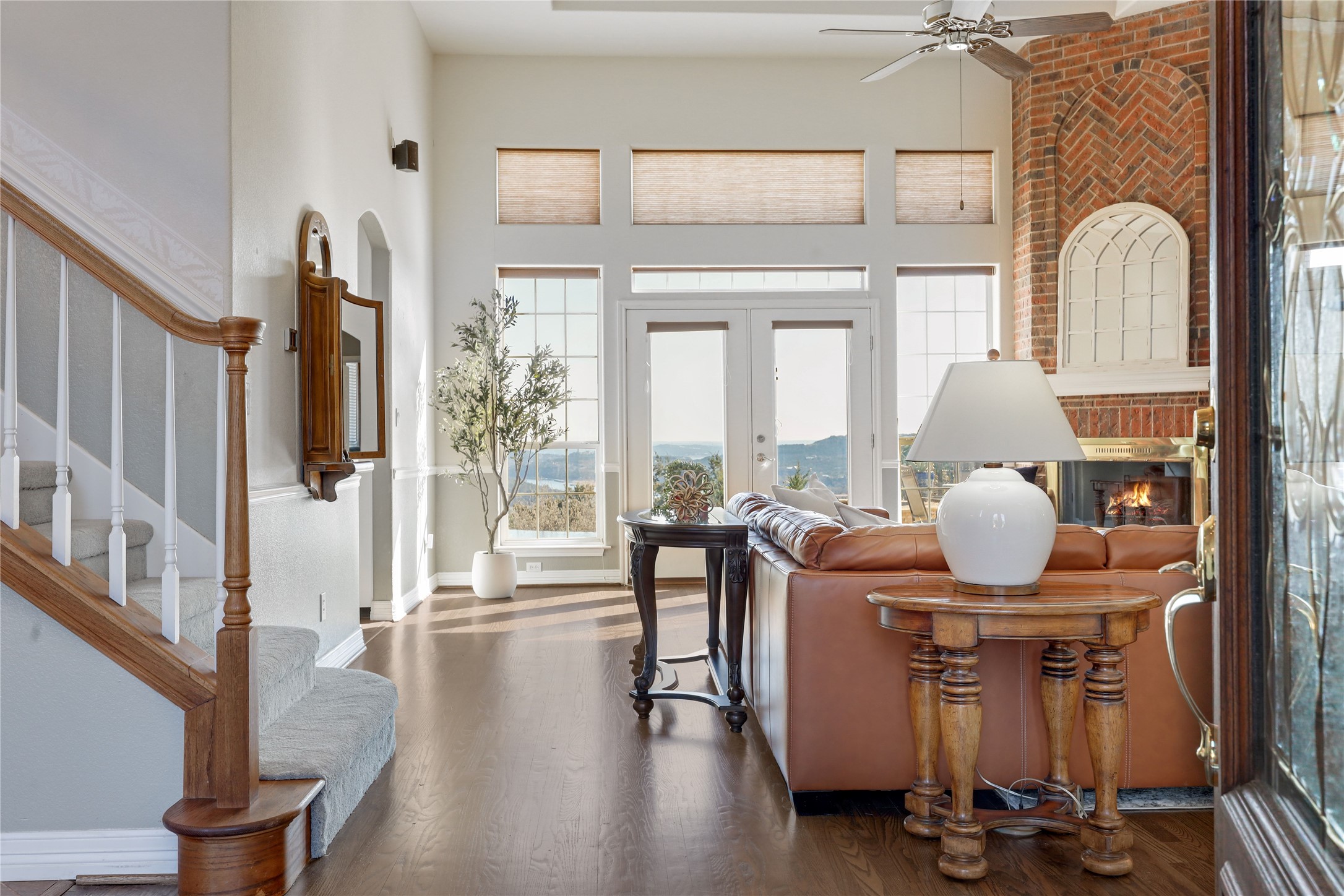 18607 White Rim Trail Jonestown, TX 78645 - Photo 6 of 40 Living room featuring a brick fireplace, healthy amount of natural light, wood finished floors, a high ceiling, and a ceiling fan