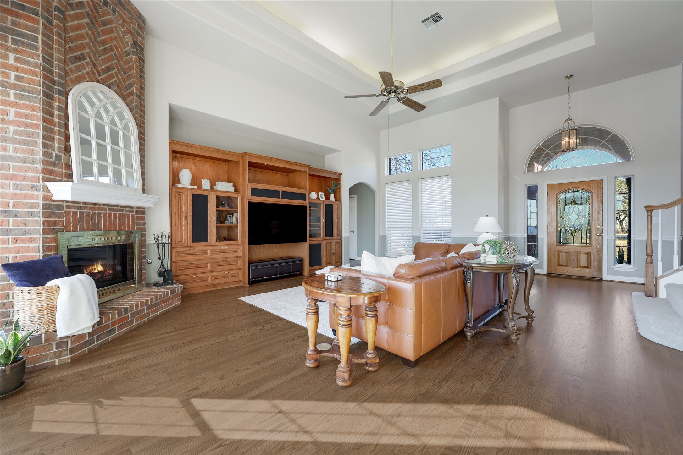 18607 White Rim Trail Jonestown, TX 78645 - Photo 7 of 40 Living room with a high ceiling, wood finished floors, a ceiling fan, a fireplace, and arched walkways