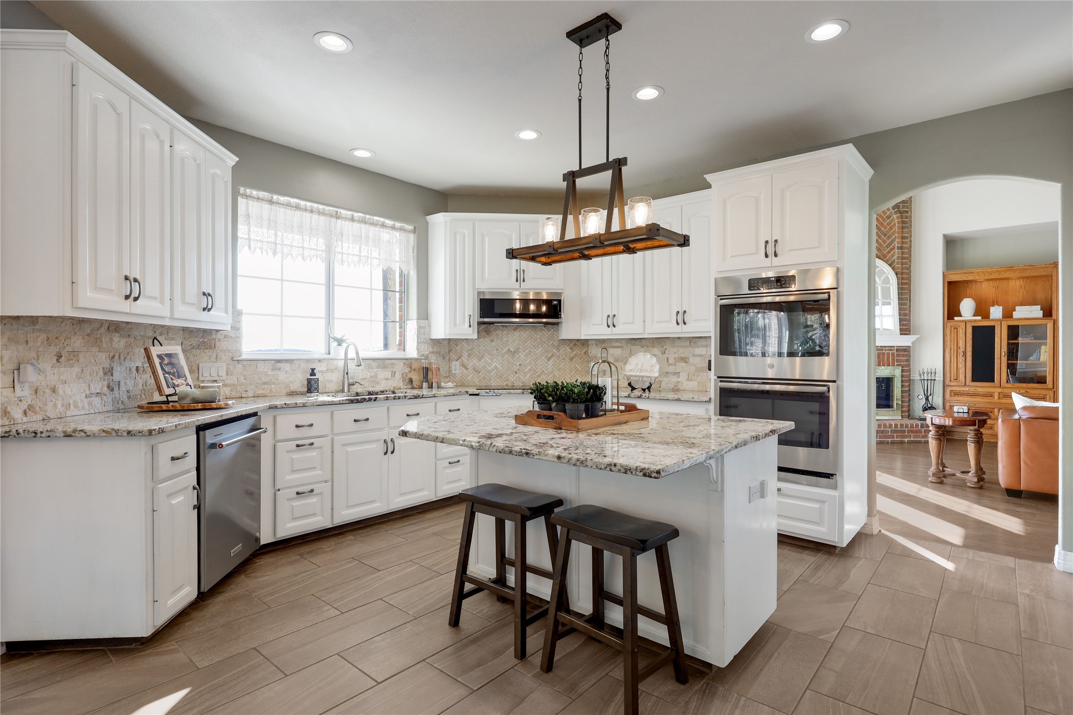 18607 White Rim Trail Jonestown, TX 78645 - Photo 10 of 40 Kitchen featuring a kitchen breakfast bar, light stone counters, a center island, stainless steel appliances, and white cabinetry