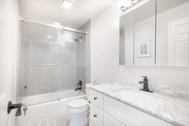 a bathroom with a granite countertop sink a toilet and shower