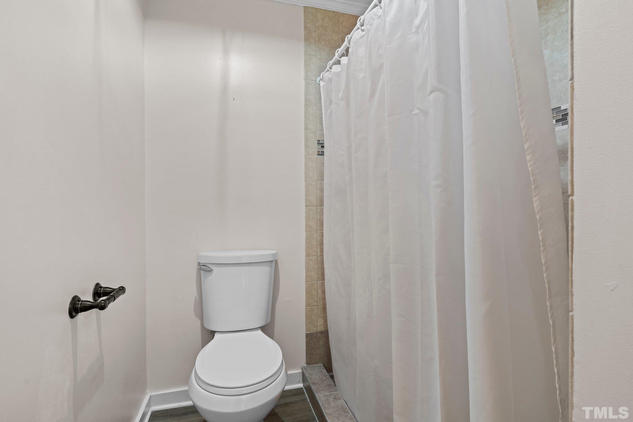 2929 Wall Store Road Garner, NC 27529 - Photo 19 of 59 a white toilet sitting next to a shower curtain