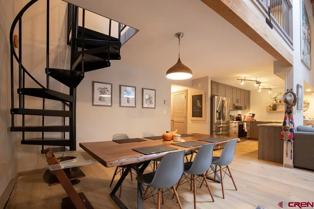 a view of a dining room and livingroom with furniture wooden floor a rug a painting and a chandelier