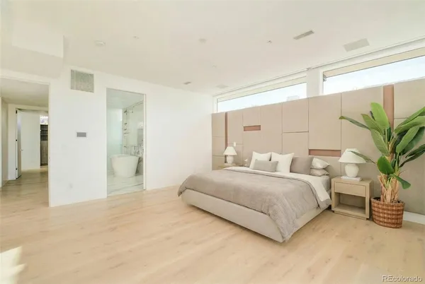 a spacious bedroom with a bed and a potted plant
