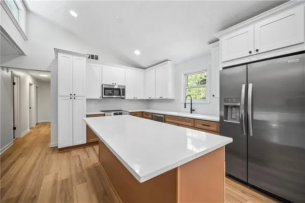 a large kitchen with stainless steel appliances a refrigerator and a stove top oven