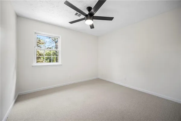 an empty room with a window and a fan