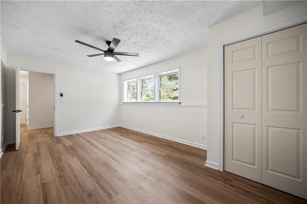 an empty room with wooden floor ceiling fan and windows