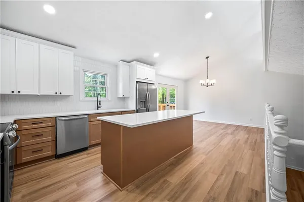 a large kitchen with kitchen island a sink a center island stainless steel appliances and a window