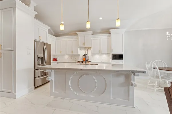 a kitchen with stainless steel appliances granite countertop a sink a stove a refrigerator and island with wooden floor