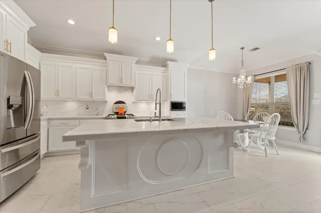 a kitchen with stainless steel appliances granite countertop a sink a stove a refrigerator and white cabinets with wooden floor