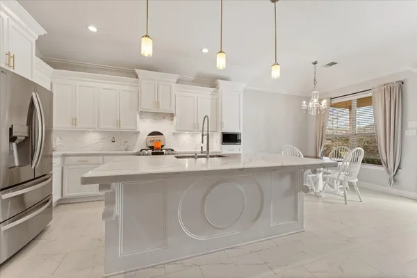 a kitchen with stainless steel appliances granite countertop a sink a stove a refrigerator and white cabinets with wooden floor