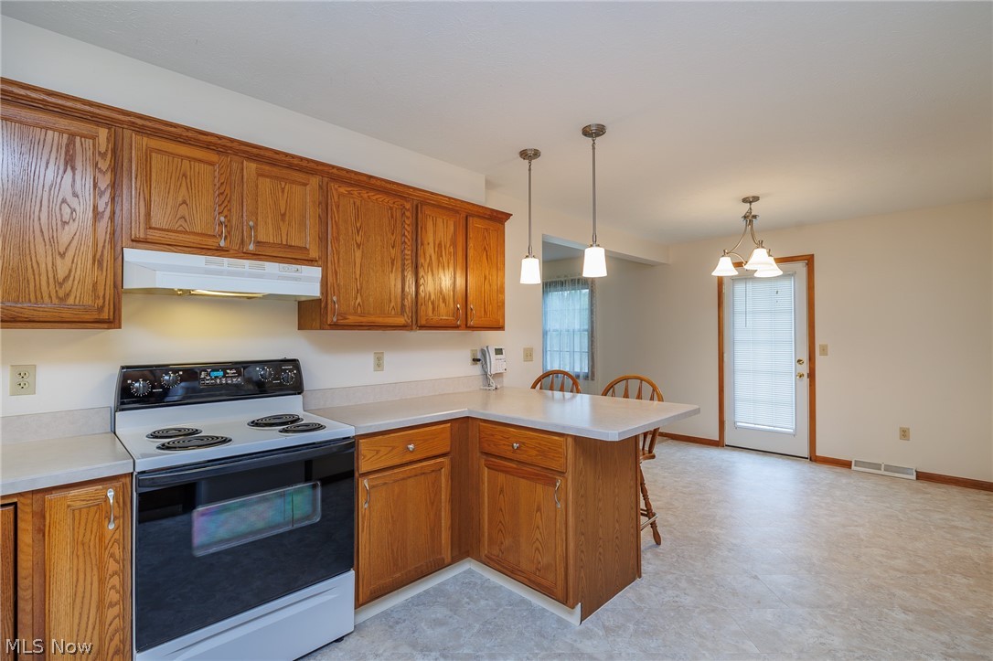 39816 Butternut Ridge Road Elyria, OH 44035 - Photo 8 of 45 Kitchen with a kitchen breakfast bar, decorative light fixtures, white electric range oven, and kitchen peninsula