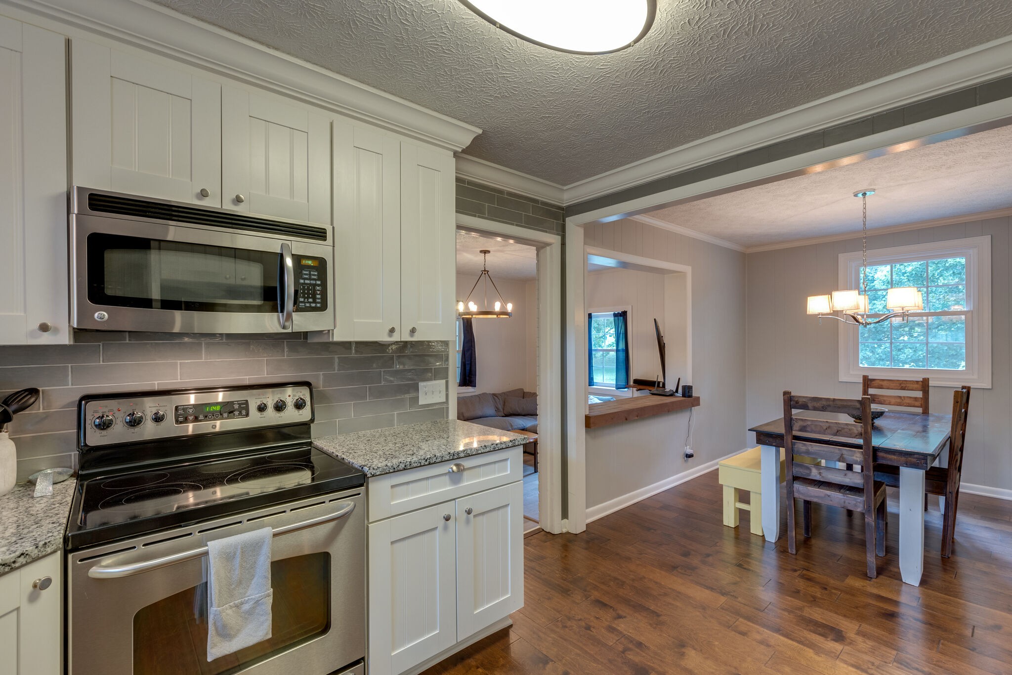 7316 Chester Road Fairview, TN 37062 - Photo 11 of 29 a kitchen with granite countertop a stove a microwave a dining table and chairs with wooden floor