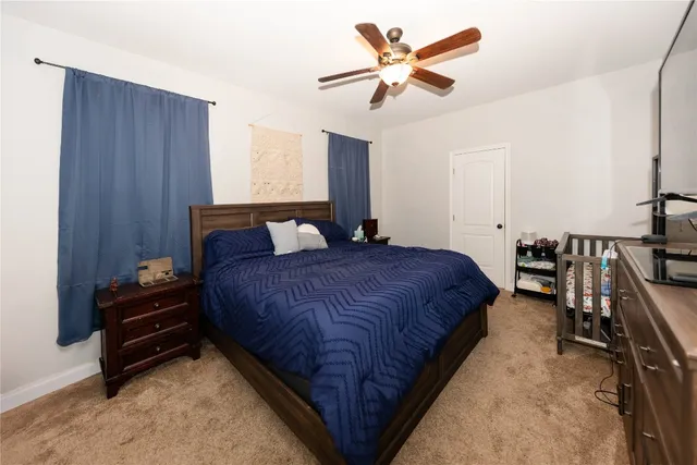 a spacious bedroom with a bed a chandelier and a dresser