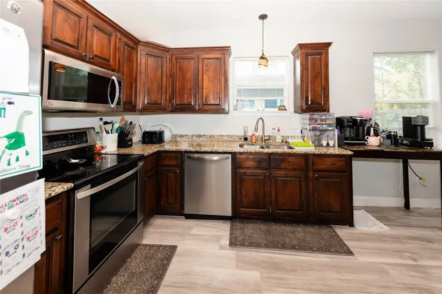 a kitchen with stainless steel appliances granite countertop a stove a sink dishwasher and a microwave oven with wooden cabinets