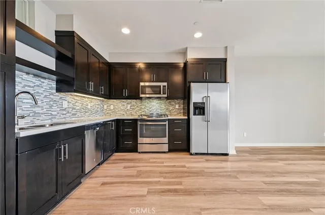 a kitchen with stainless steel appliances kitchen island granite countertop a refrigerator and a stove top oven