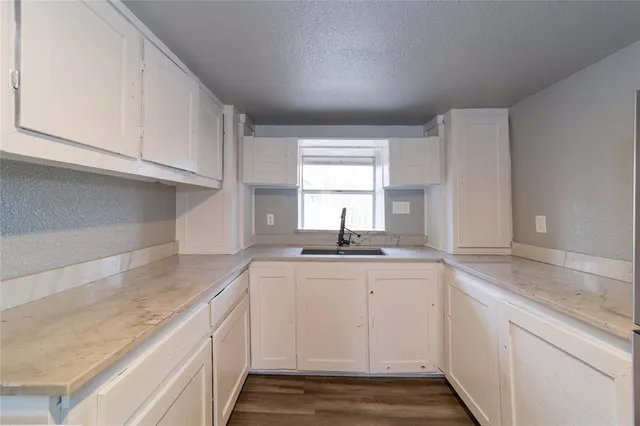 a kitchen with granite countertop white cabinets and a sink