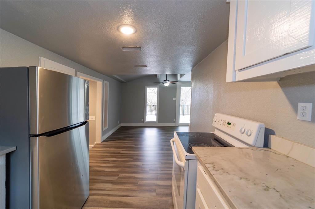 4838 Williams Spring Road Fort Worth, TX 76135 - Photo 7 of 17 a view of a refrigerator in kitchen and wooden floor