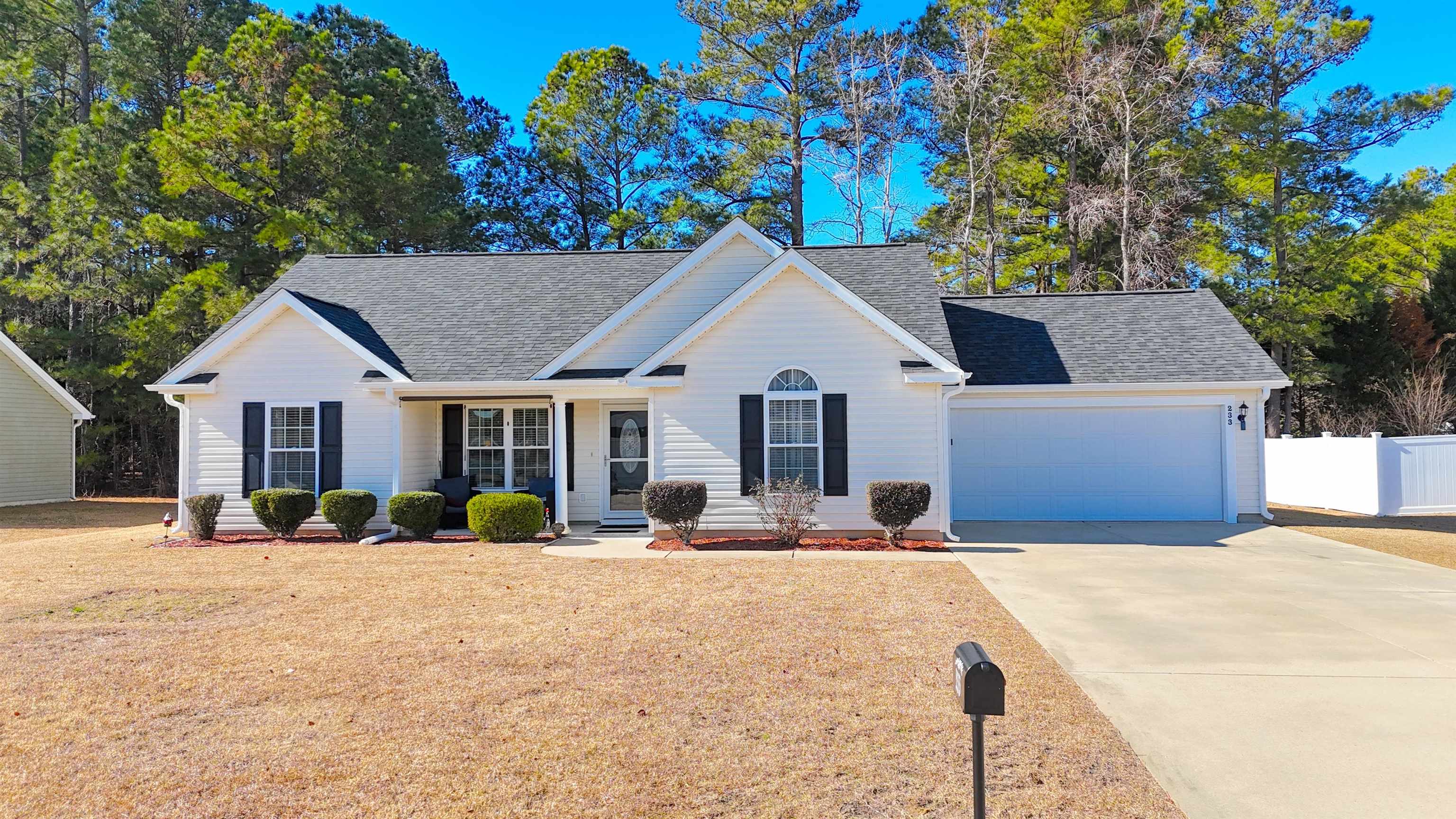 View of front of home with a shingled roof, covered porch, driveway, and an attached garage