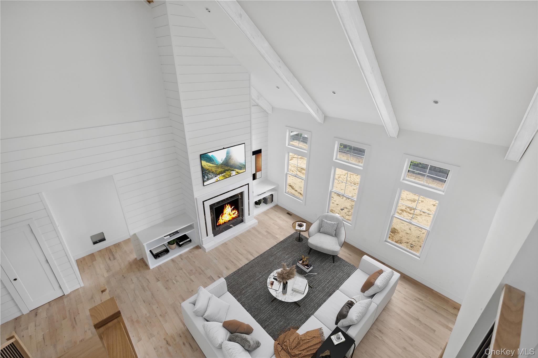 74 Tyler Drive Riverhead, NY 11901 - Photo 15 of 23 Living area with lofted ceiling with beams, a lit fireplace, and wood finished floors