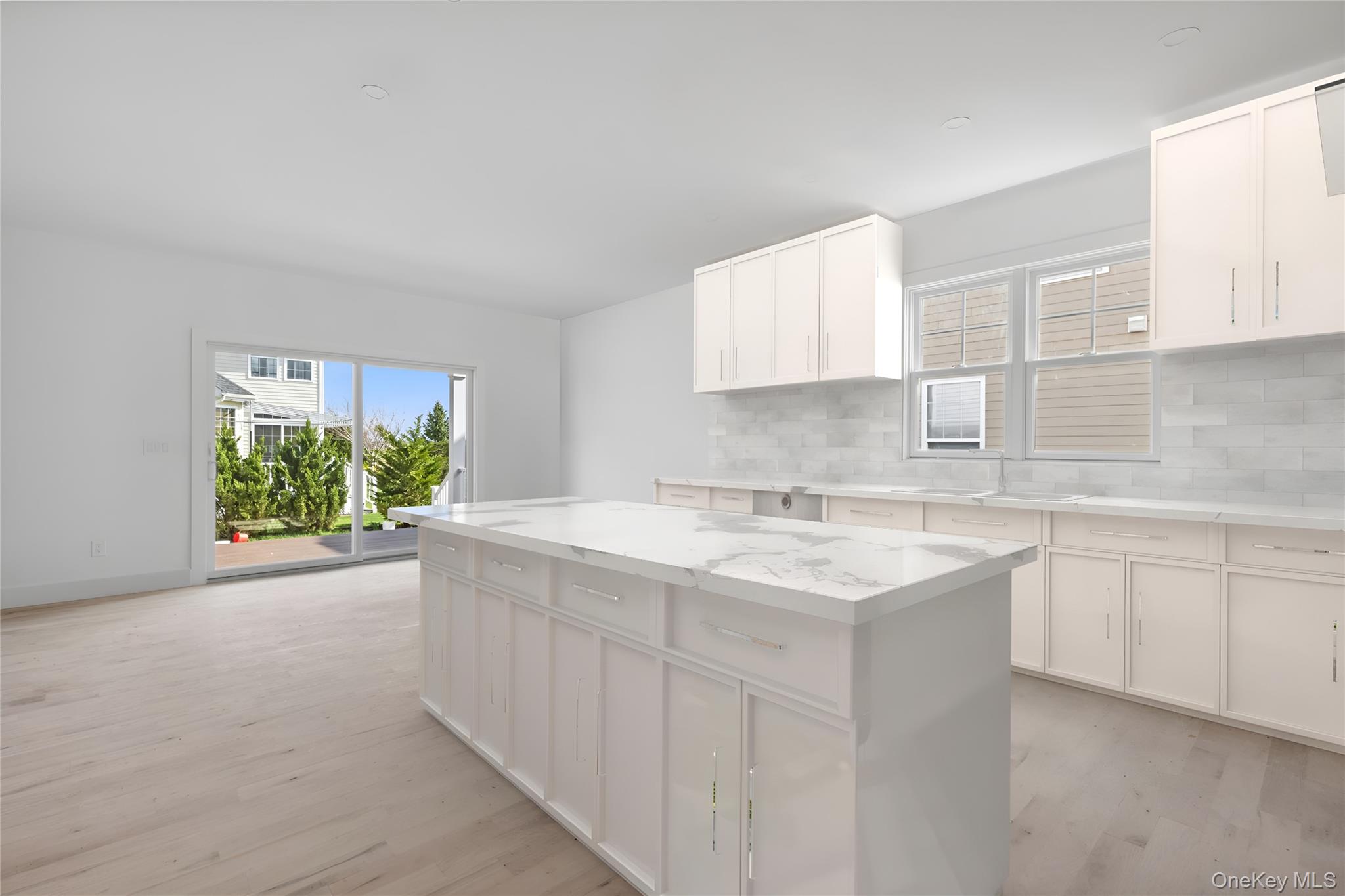 74 Tyler Drive Riverhead, NY 11901 - Photo 7 of 23 Kitchen featuring backsplash, a center island, white cabinetry, and light wood-style flooring