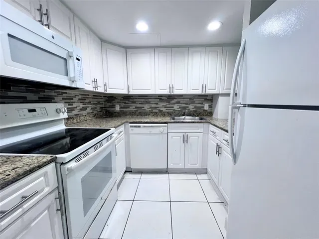 a kitchen with white cabinets and white appliances
