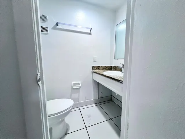 a bathroom with a granite countertop toilet and a sink