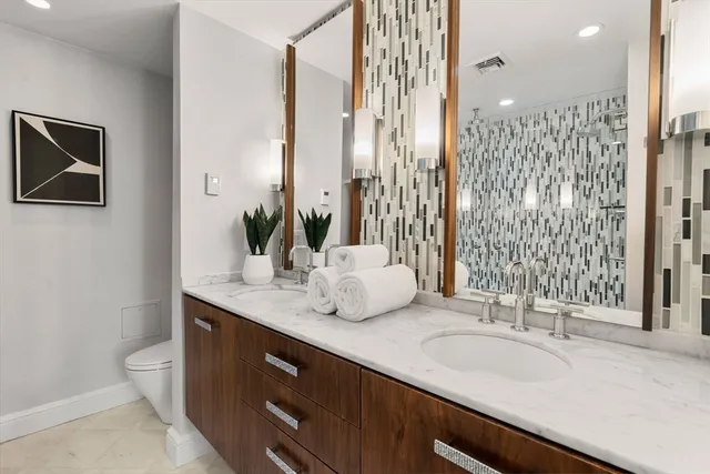 a bathroom with double vanity sinks a toilet a mirror and shower