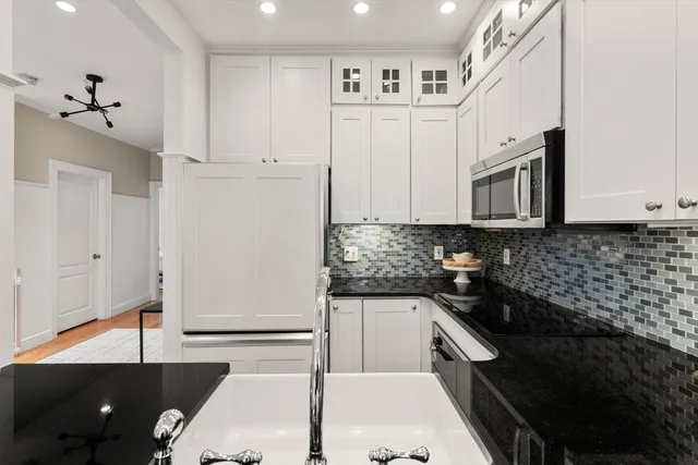 a kitchen with granite countertop white cabinets and stainless steel appliances