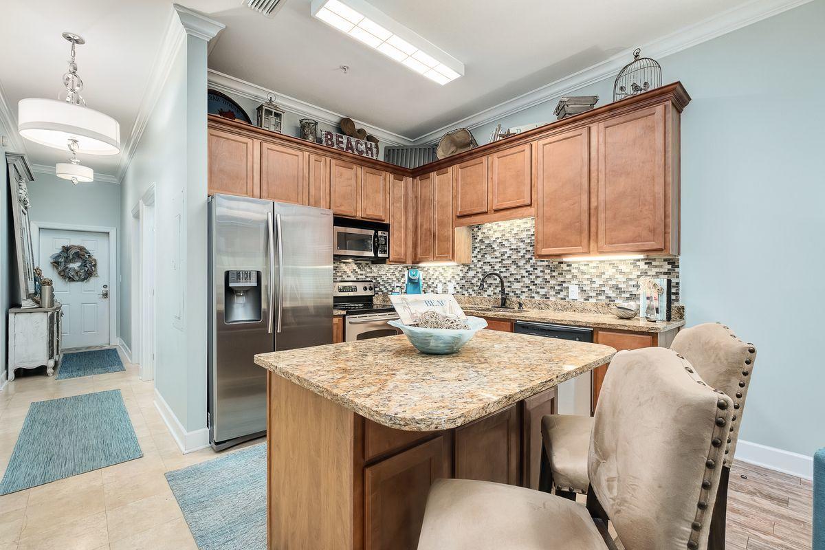 231 Somerset Bridge Road, Unit 2205 Santa Rosa Beach, FL 32459 - Photo 6 of 40 a kitchen with granite countertop kitchen island stainless steel appliances a table chairs and a refrigerator