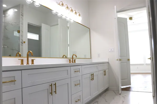 a kitchen with stainless steel appliances granite countertop a refrigerator a stove a sink and white cabinets with wooden floor