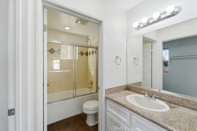 a bathroom with a granite countertop sink toilet a mirror a vanity and shower