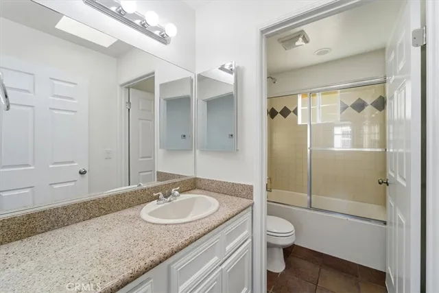 a bathroom with a granite countertop sink a toilet a mirror and shower