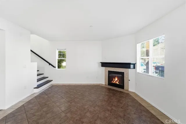 a view of an empty room with wooden floor fireplace and a window