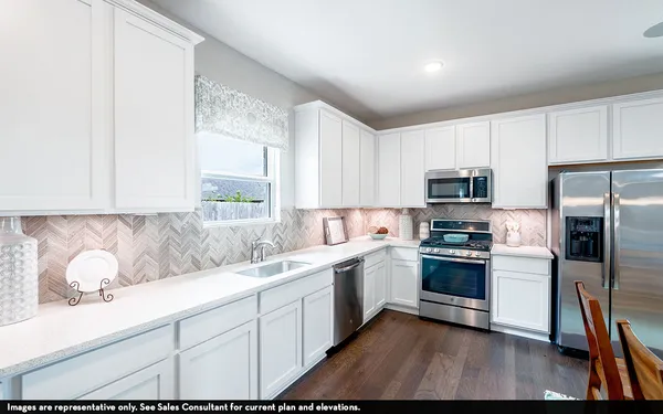 a kitchen with stainless steel appliances white cabinets a sink a stove a refrigerator and microwave