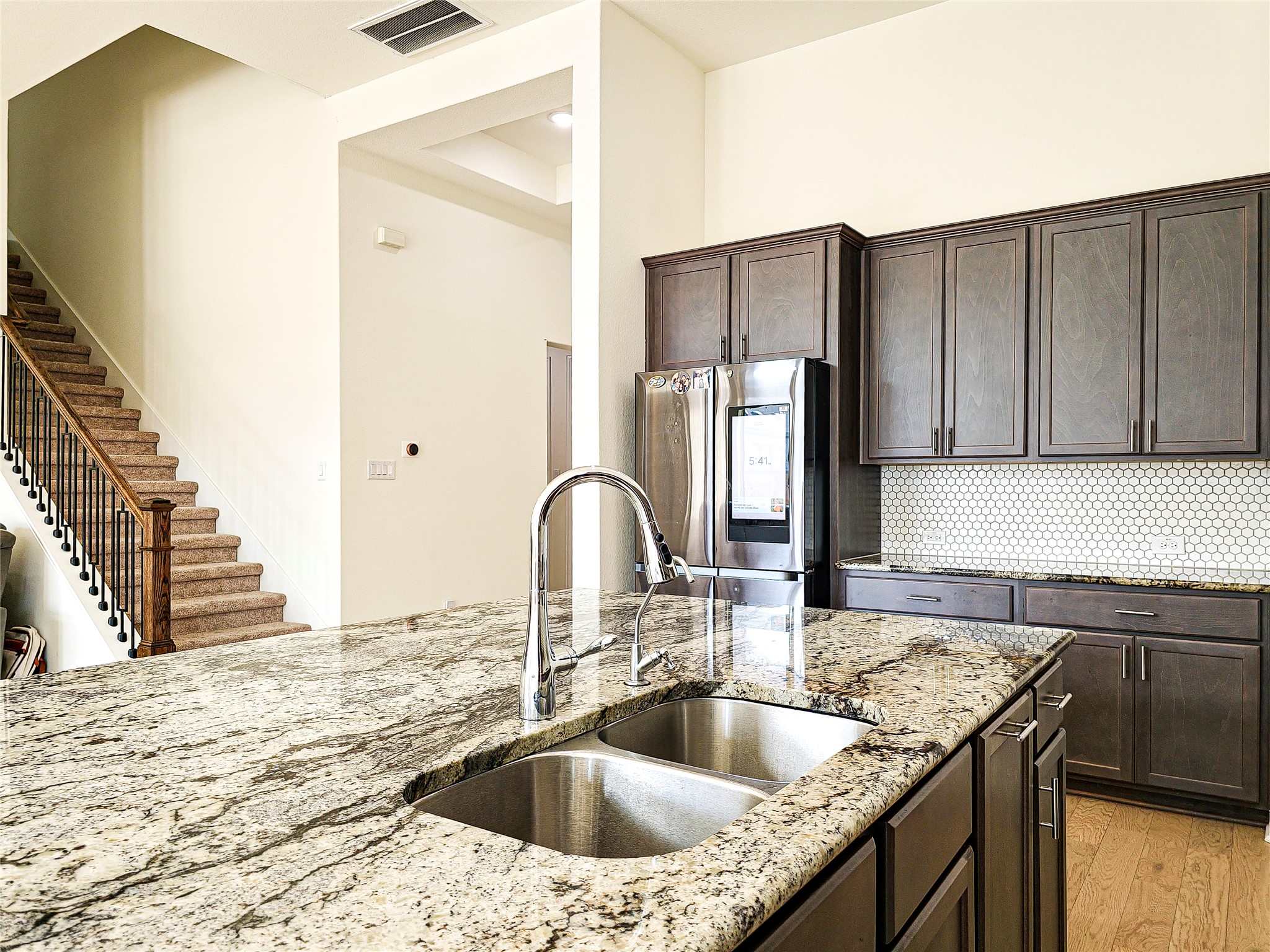 813 Sunny Ridge Drive Leander, TX 78641 - Photo 5 of 32 A well-appointed kitchen features a large island and ample cabinet space, seamlessly connecting to an elegant staircase.