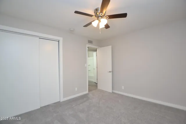 an empty room with a chandelier fan and windows