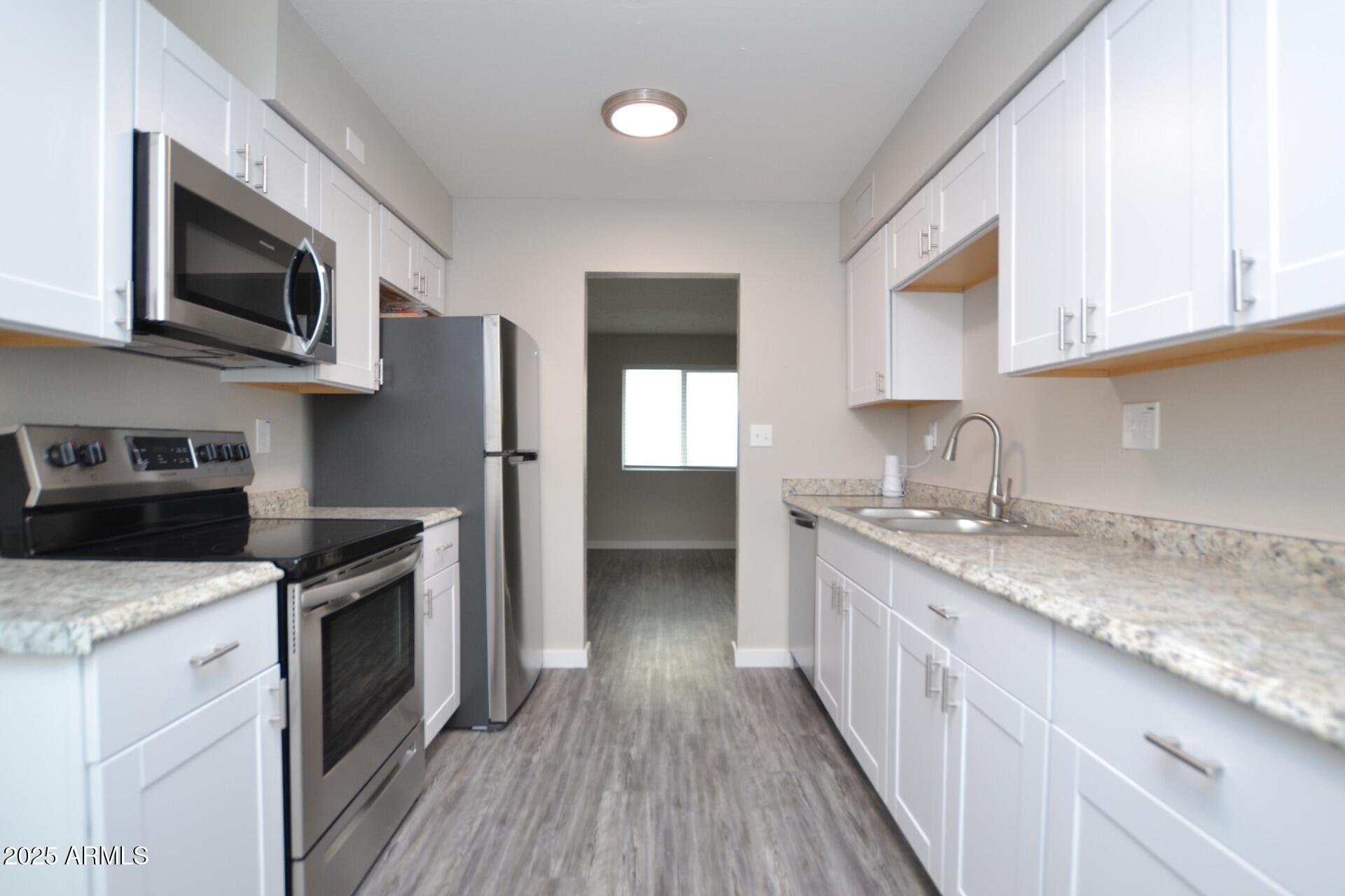 2202 West Devonshire Avenue, Unit 3 Phoenix, AZ 85015 - Photo 4 of 16 a kitchen with stainless steel appliances granite countertop a stove a sink and a microwave