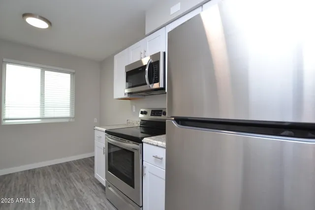 a kitchen with granite countertop cabinets stainless steel appliances and window