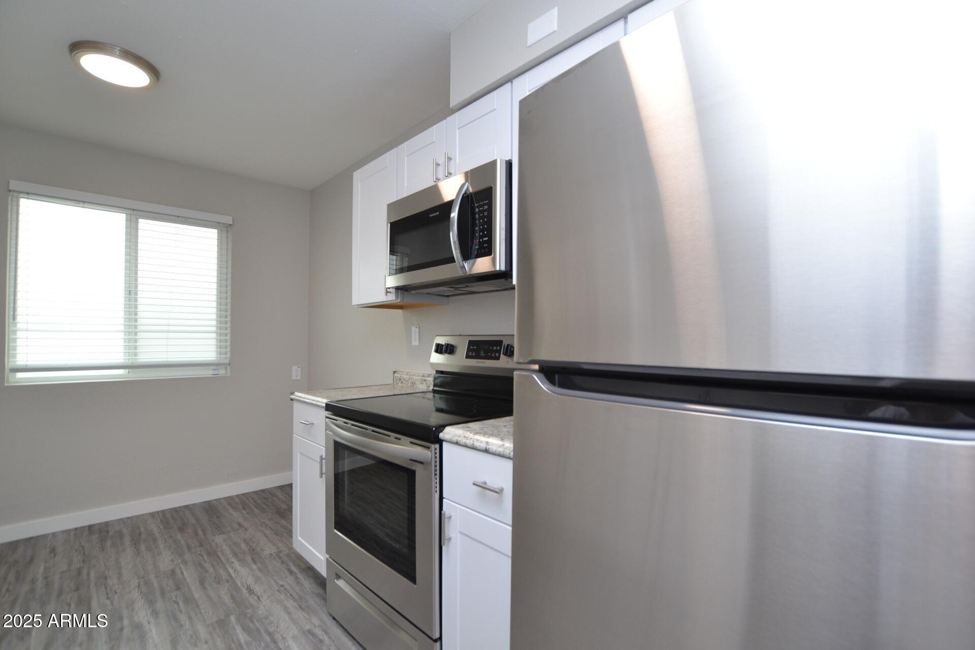 2202 West Devonshire Avenue, Unit 3 Phoenix, AZ 85015 - Photo 5 of 16 a kitchen with granite countertop cabinets stainless steel appliances and window