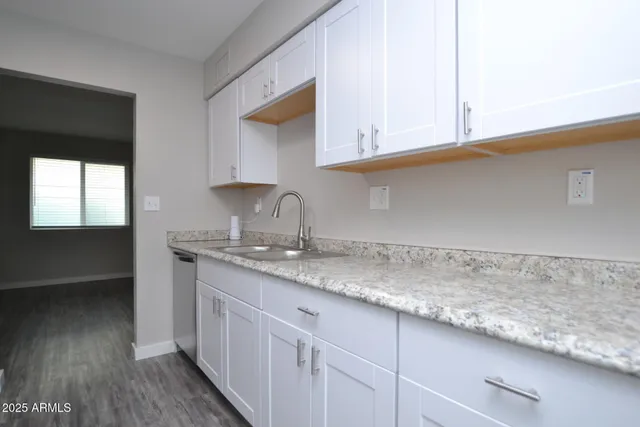 a kitchen with granite countertop white cabinets and a sink