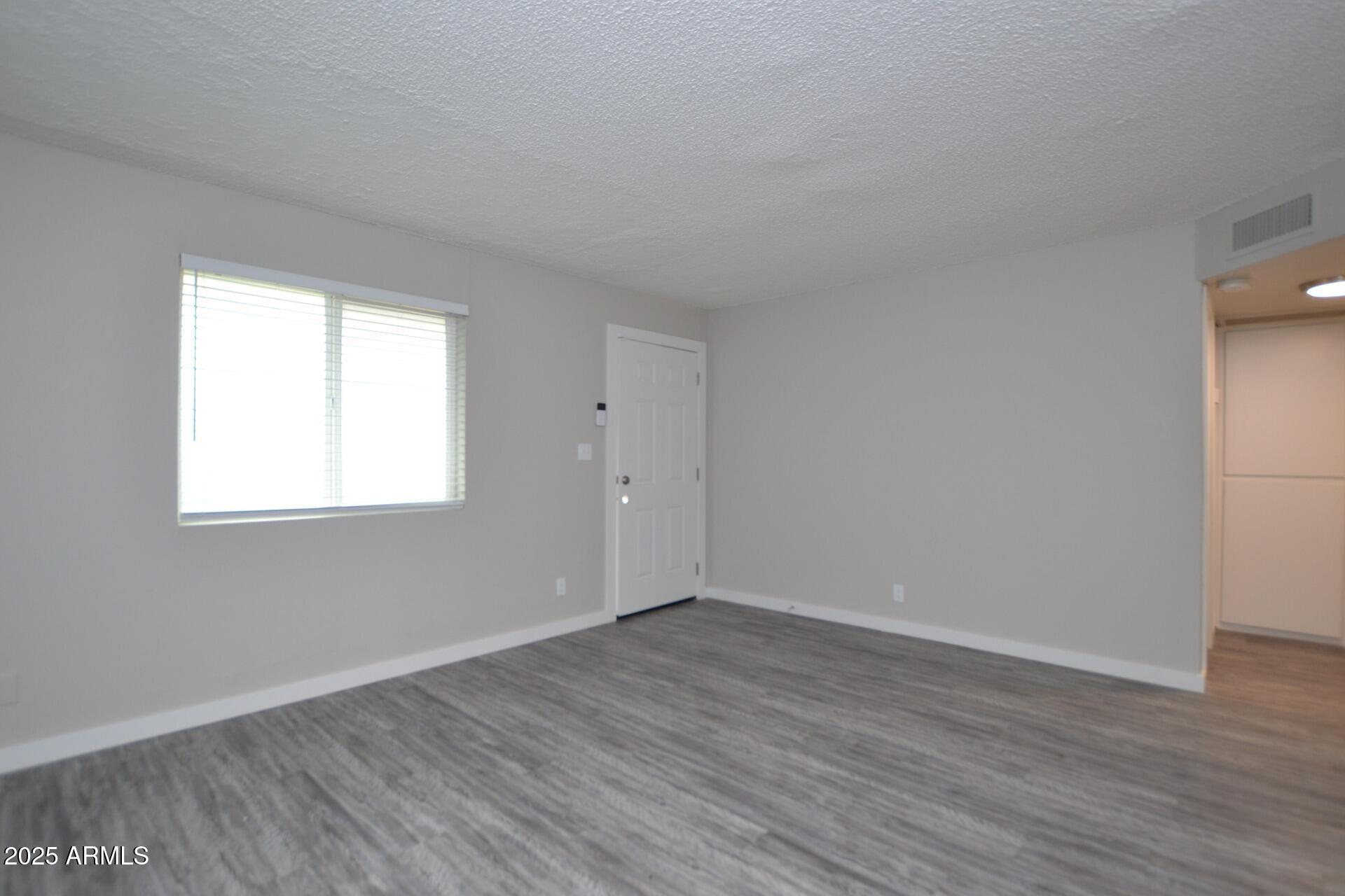 2202 West Devonshire Avenue, Unit 3 Phoenix, AZ 85015 - Photo 8 of 16 a view of an empty room with wooden floor and a window
