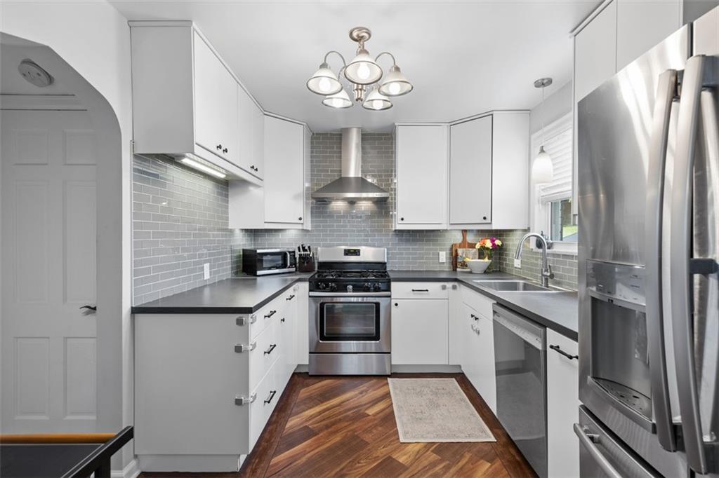 8 Court Place McKees Rocks, PA 15136 - Photo 9 of 32 a kitchen with stainless steel appliances granite countertop a stove a sink dishwasher a refrigerator and white cabinets with wooden floor