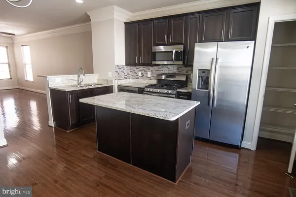 a kitchen with kitchen island granite countertop a sink stove and refrigerator