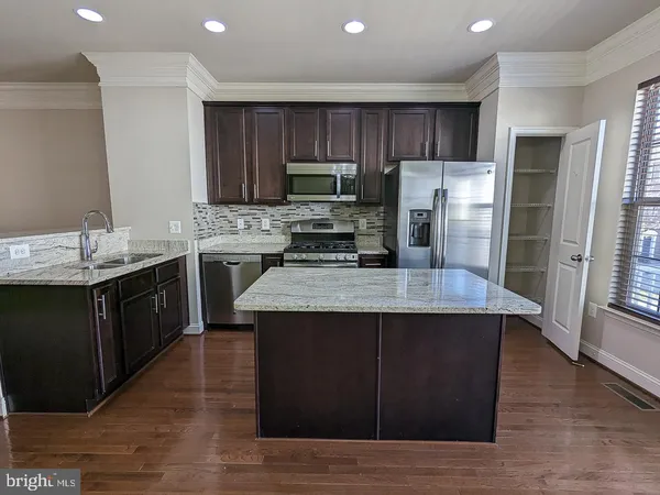 a kitchen with kitchen island granite countertop wooden cabinets a refrigerator and a sink