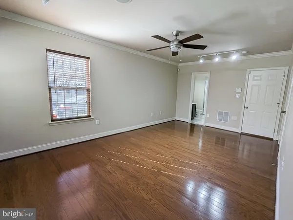 a view of empty room with wooden floor and fan