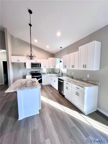 a kitchen with stainless steel appliances granite countertop a sink a stove a refrigerator and island with wooden floor